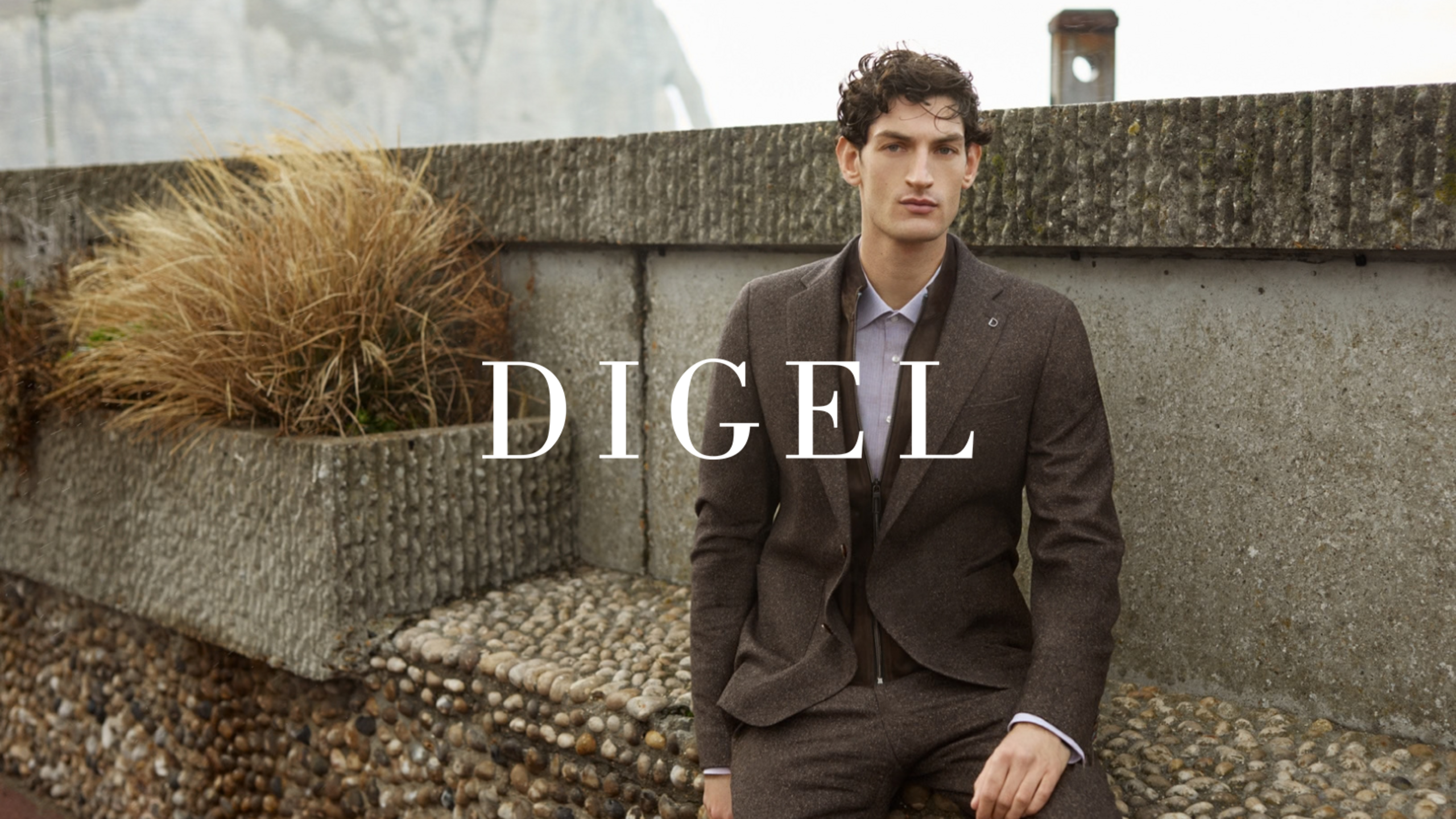 A man in an elegant Digel suit against a stone urban backdrop.