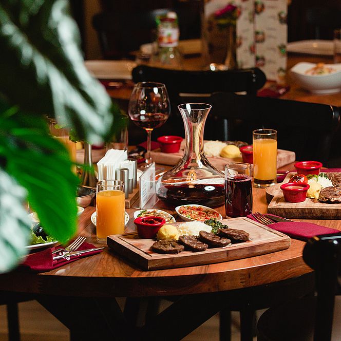 Stół w restauracji z elegancko podanymi daniami, karafką wina i różnorodnymi napojami