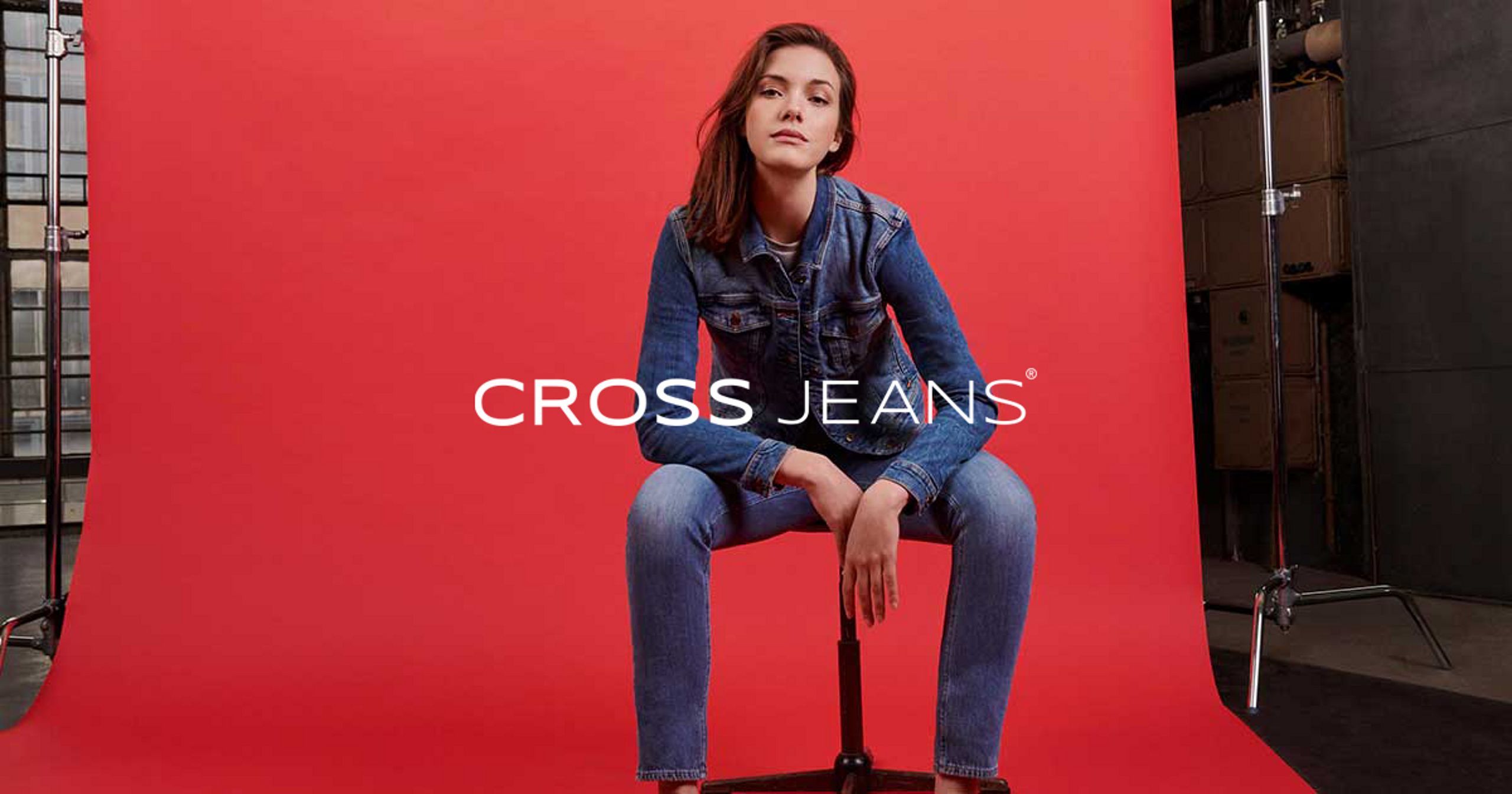 Kobieta w jeansowej stylizacji Cross Jeans na czerwonym tle.