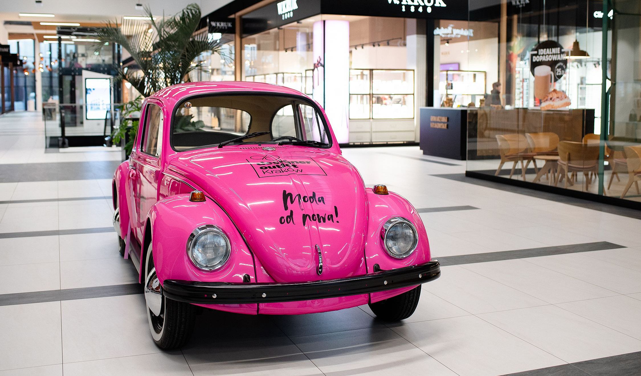 A pink classic car stealing the spotlight at the shopping mall