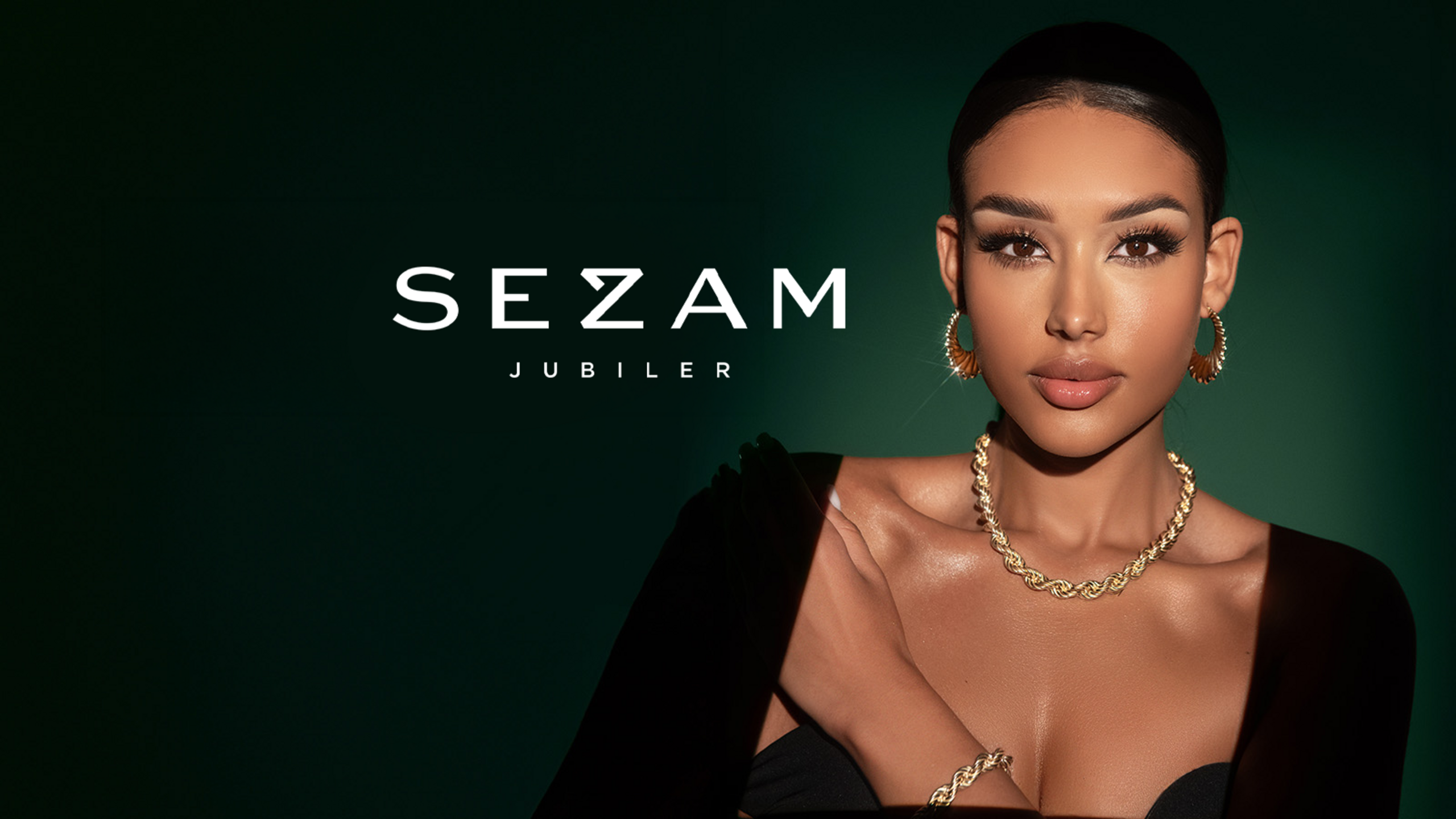 A woman in a black outfit showcasing Sezam Jubiler gold jewelry against a dark green background.
