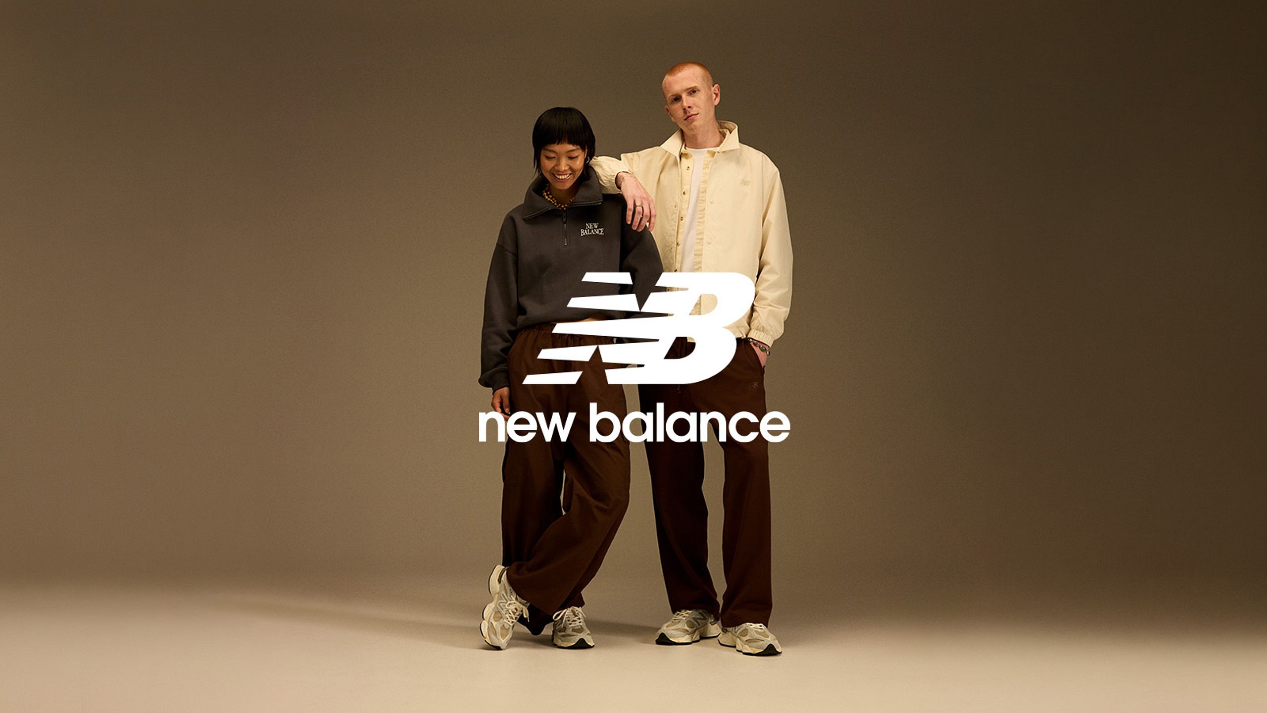Para w stylizacjach New Balance na neutralnym tle.
