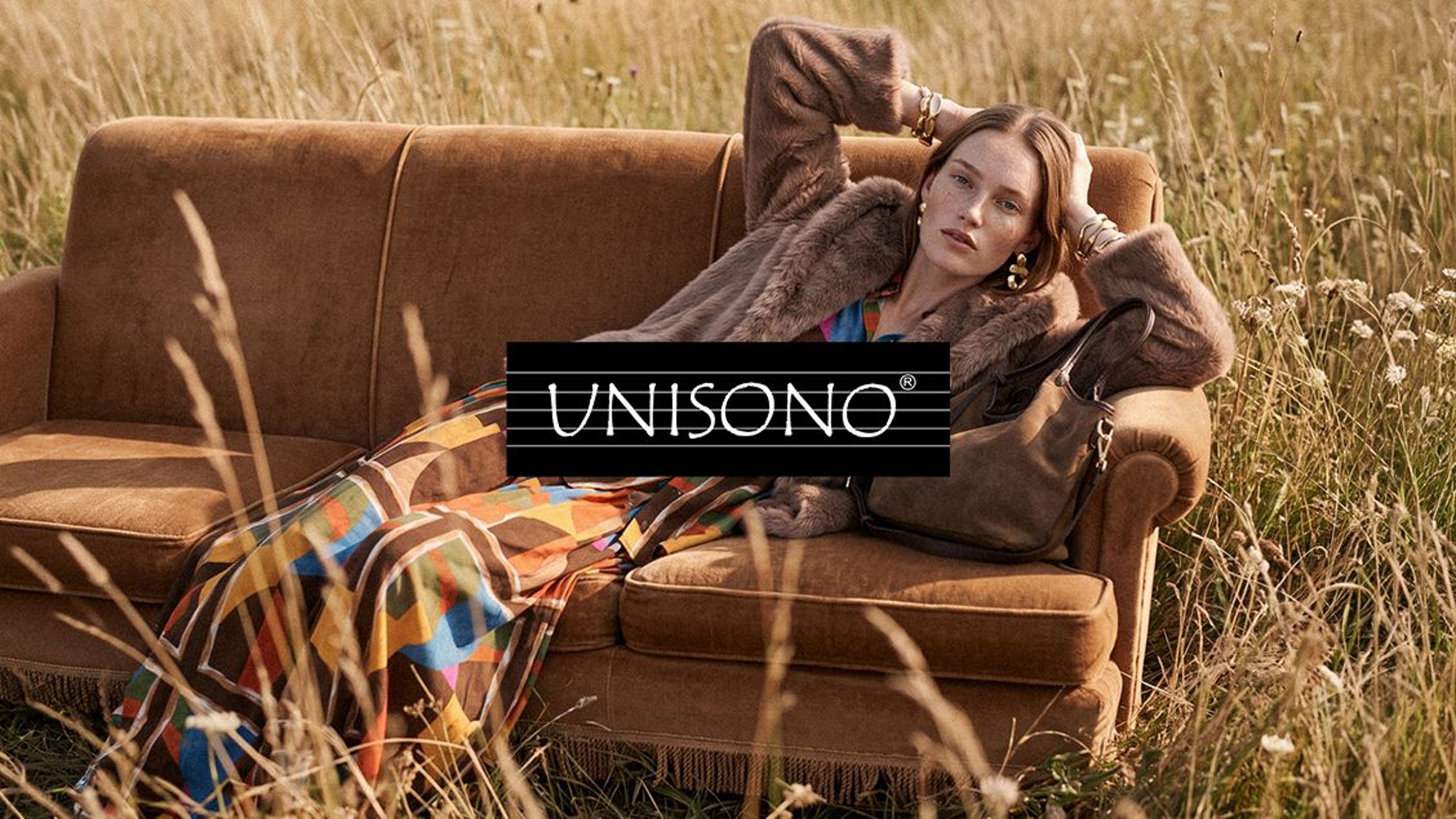 Model in a UNISONO outfit on a sofa surrounded by tall grass.