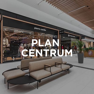 Wnętrze Designer Outlet Kraków z widoczną witryną sklepu Greenpoint i napisem „Plan Centrum” na środku obrazu.