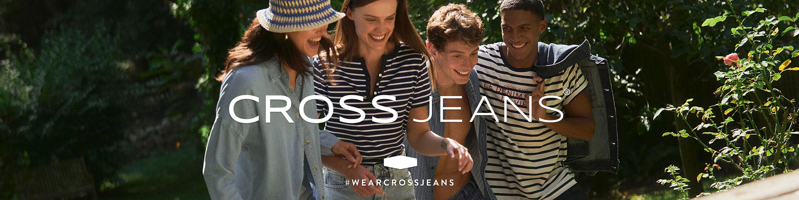 Four young people dressed in summer outfits – jeans and striped shirts – are walking and laughing together in a sunny, green garden. At the center is the white “CROSS JEANS®” logo, with the hashtag #WEARCROSSJEANS underneath.