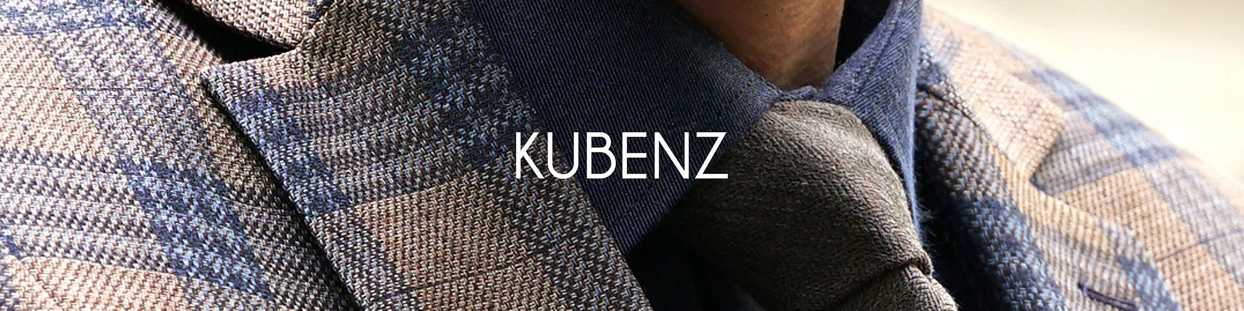 Zbliżenie na elegancki męski strój – krawat, koszula w ciemnym odcieniu i marynarka w kratę w odcieniach niebieskiego i beżu. Na środku widnieje białe logo „KUBENZ”.