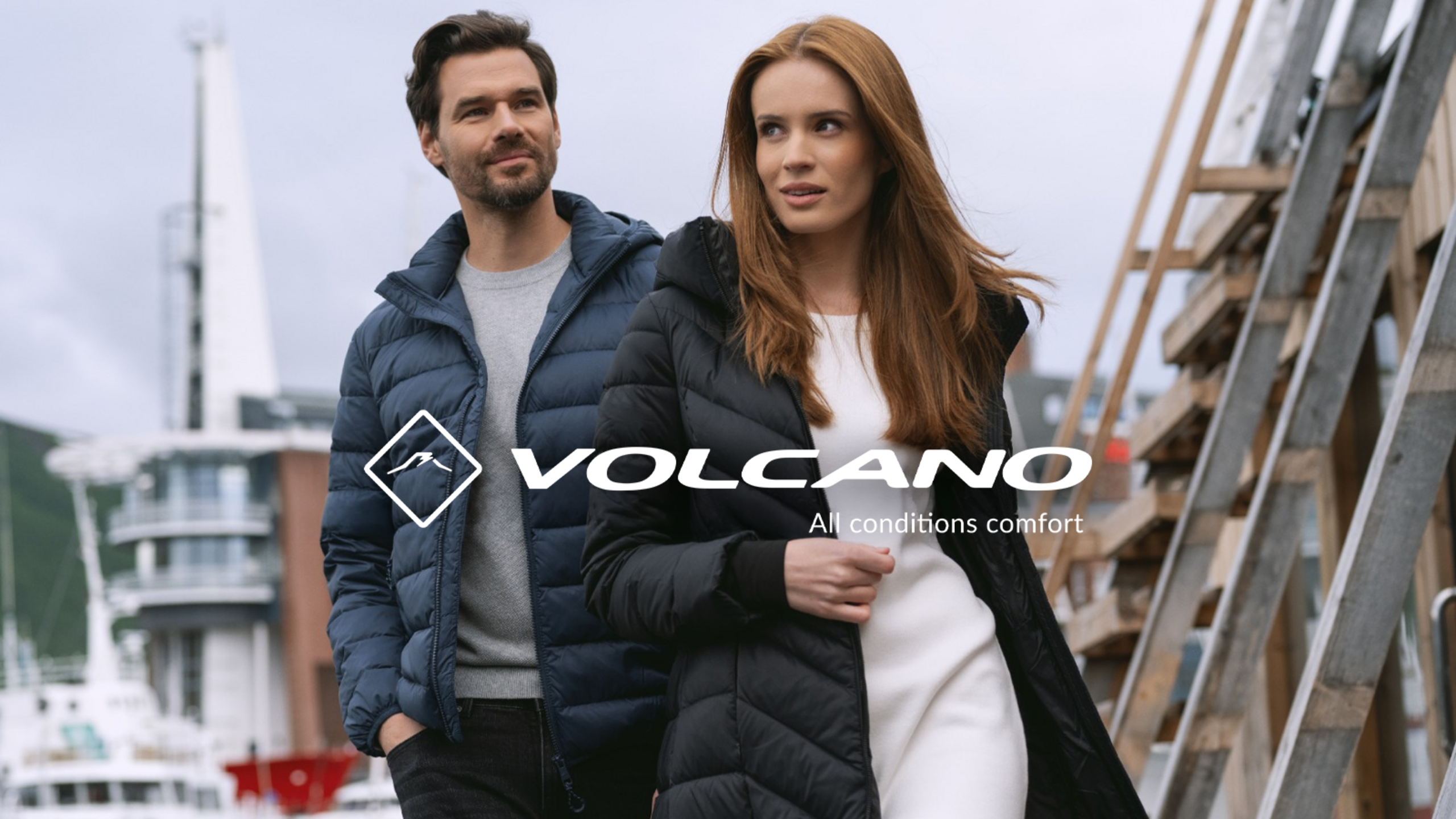 A couple wearing Volcano puffer jackets against an urban backdrop.