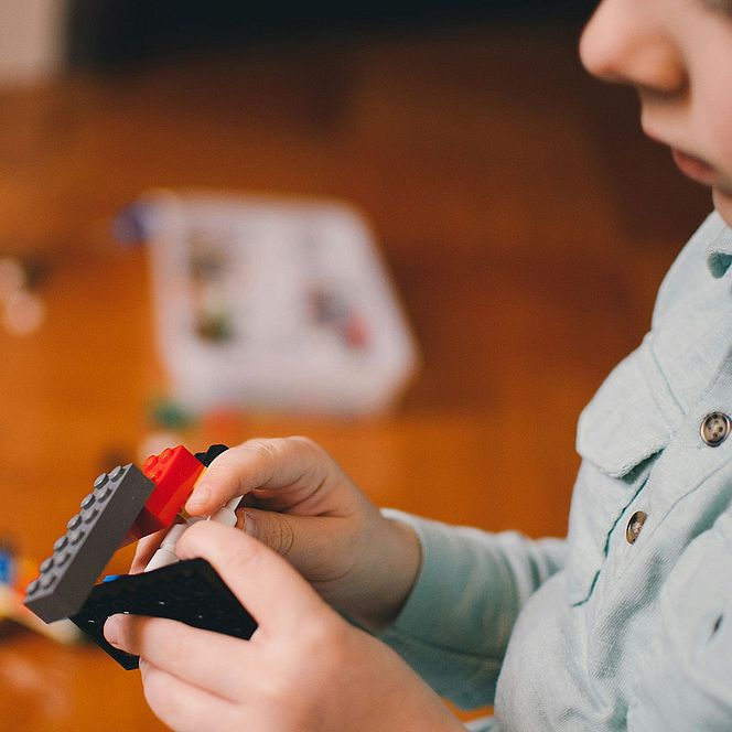 A child in a light shirt playing with colorful bricks — symbolizing creativity and development in a child-friendly space.