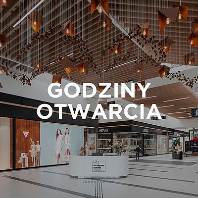 Wnętrze Designer Outlet Kraków z widoczną witryną sklepu Greenpoint i napisem „Godziny otwarcia” na środku obrazu.