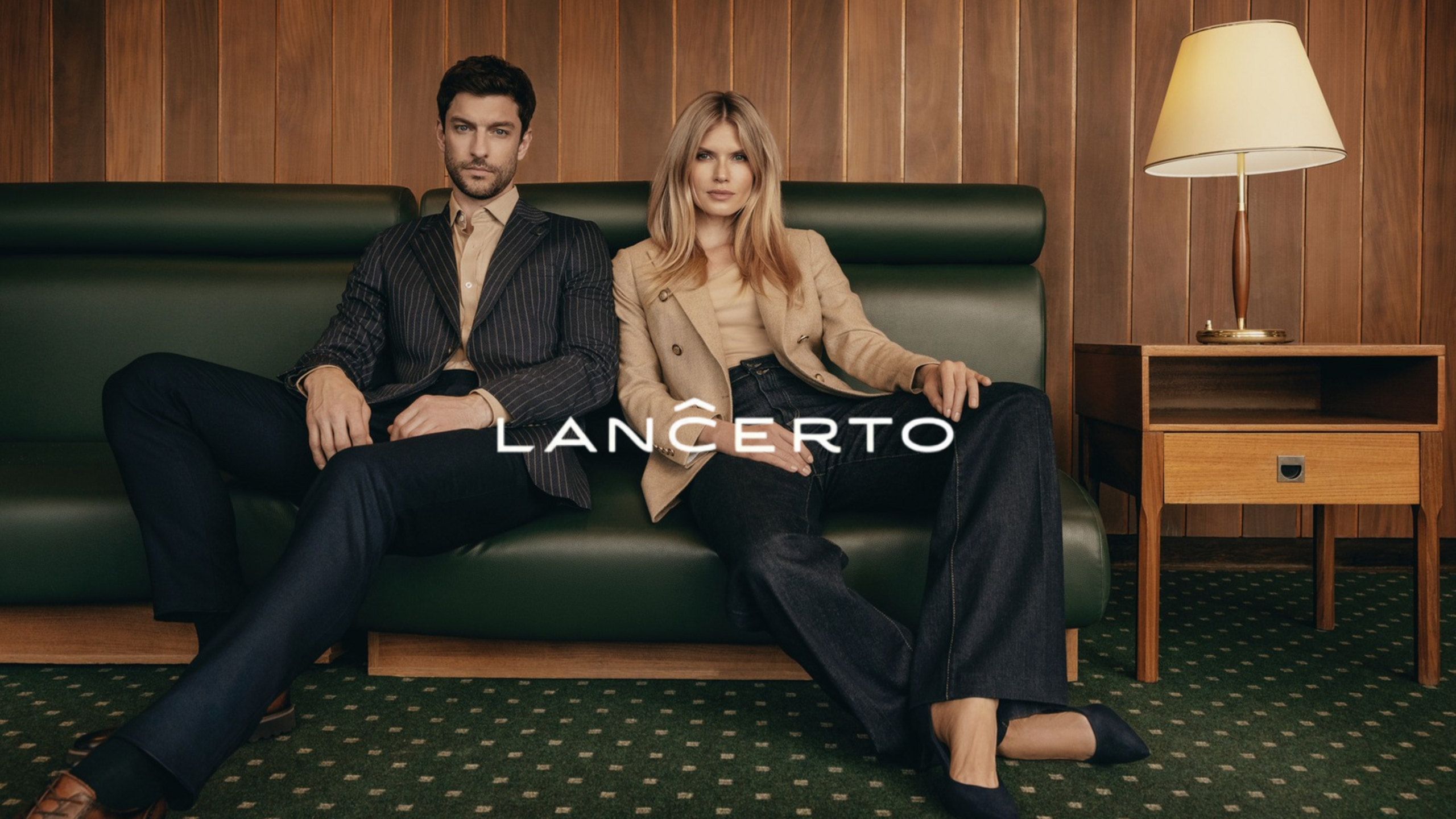 A couple in elegant Lancerto outfits sitting on a leather sofa in a stylish interior.