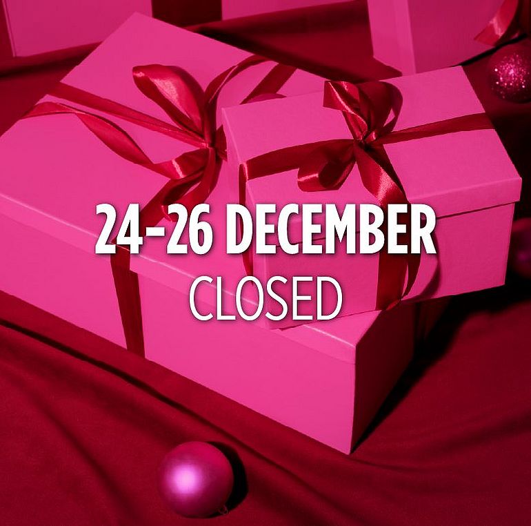 A woman in a pink dress holding a purple bauble, with gifts in the background.