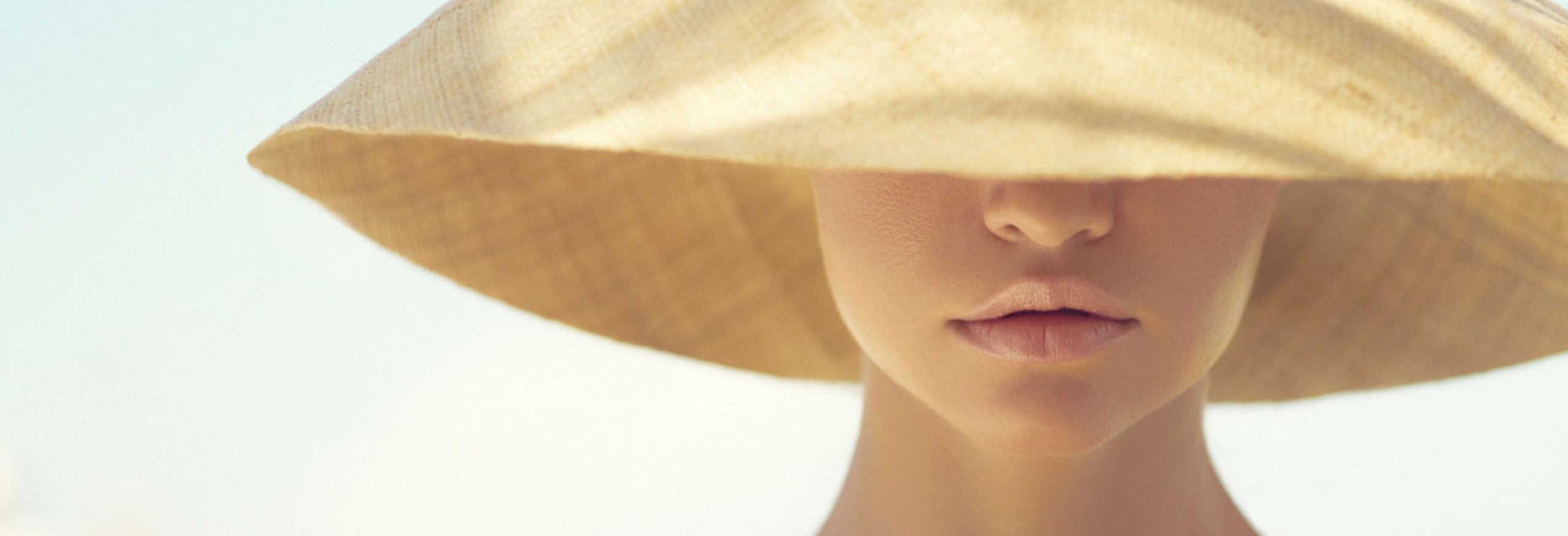 A woman wears a sun hat that covers half of her face