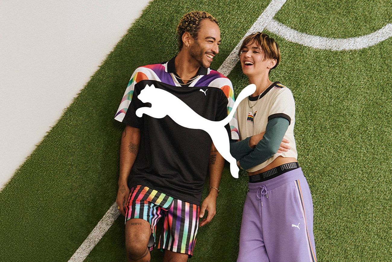A standing couple wearing Puma clothing and laughing, in the background is a pattern with part of a football pitch