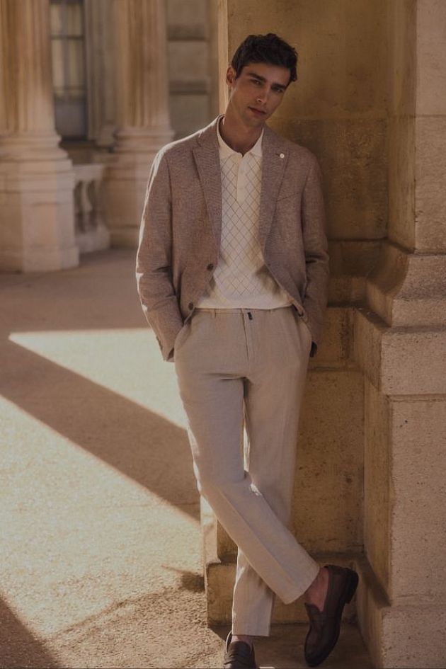 Mężczyzna w eleganckiej stylizacji Pierre Cardin w klasycznym, zabytkowym wnętrzu.