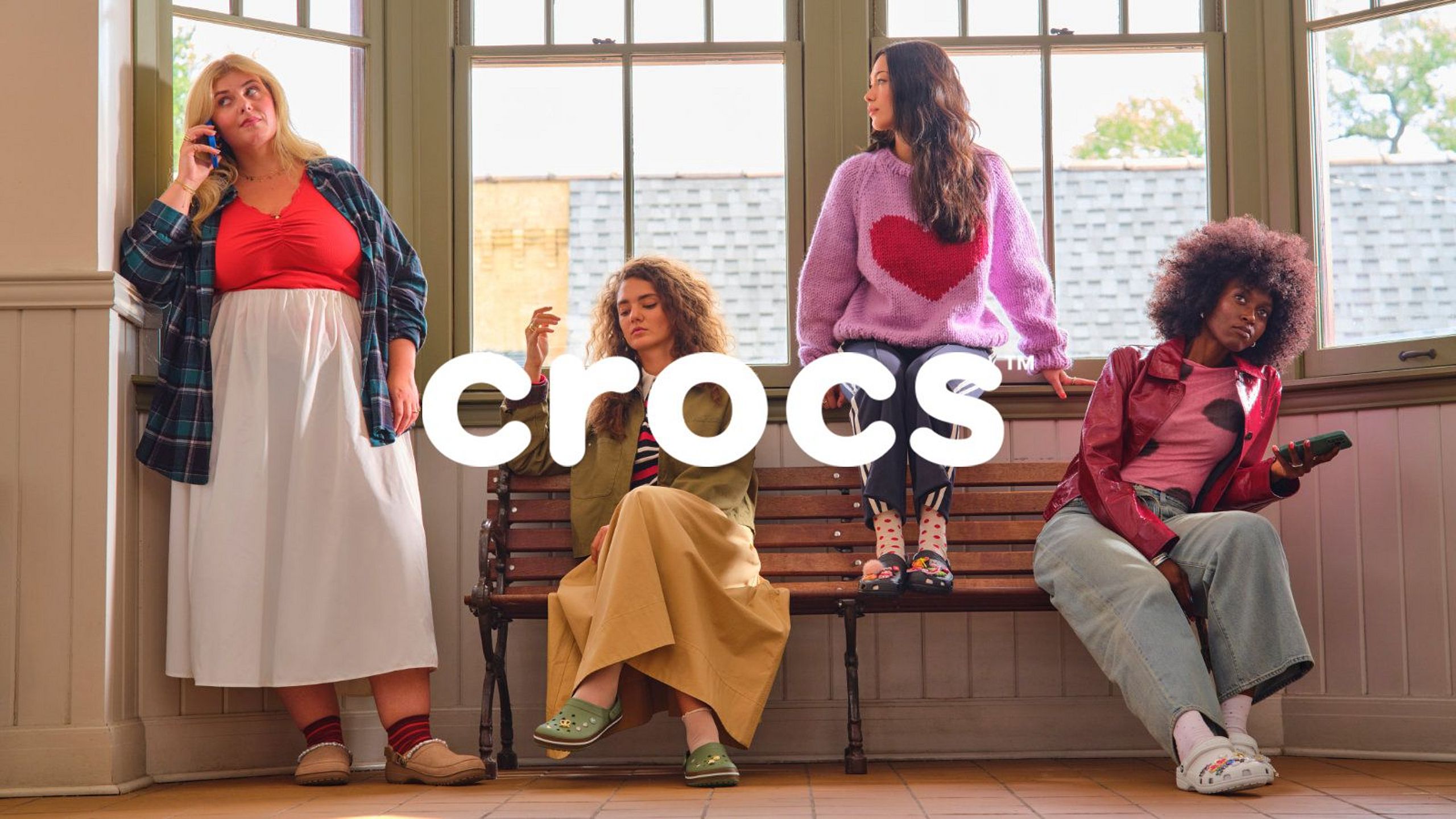 Four women in colorful Crocs outfits in a bright interior.