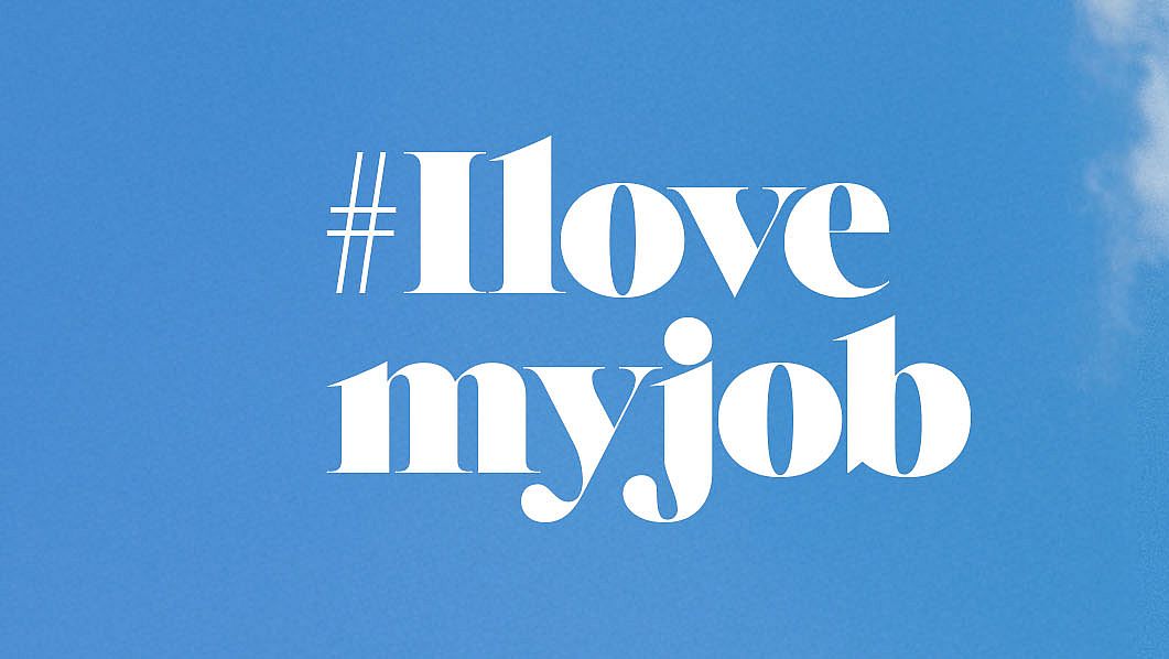 Kobieta w różowej marynarce patrząca z dumą w obiektyw na tle błękitnego nieba. Po lewej stronie napis: „#Ilovemyjob”.