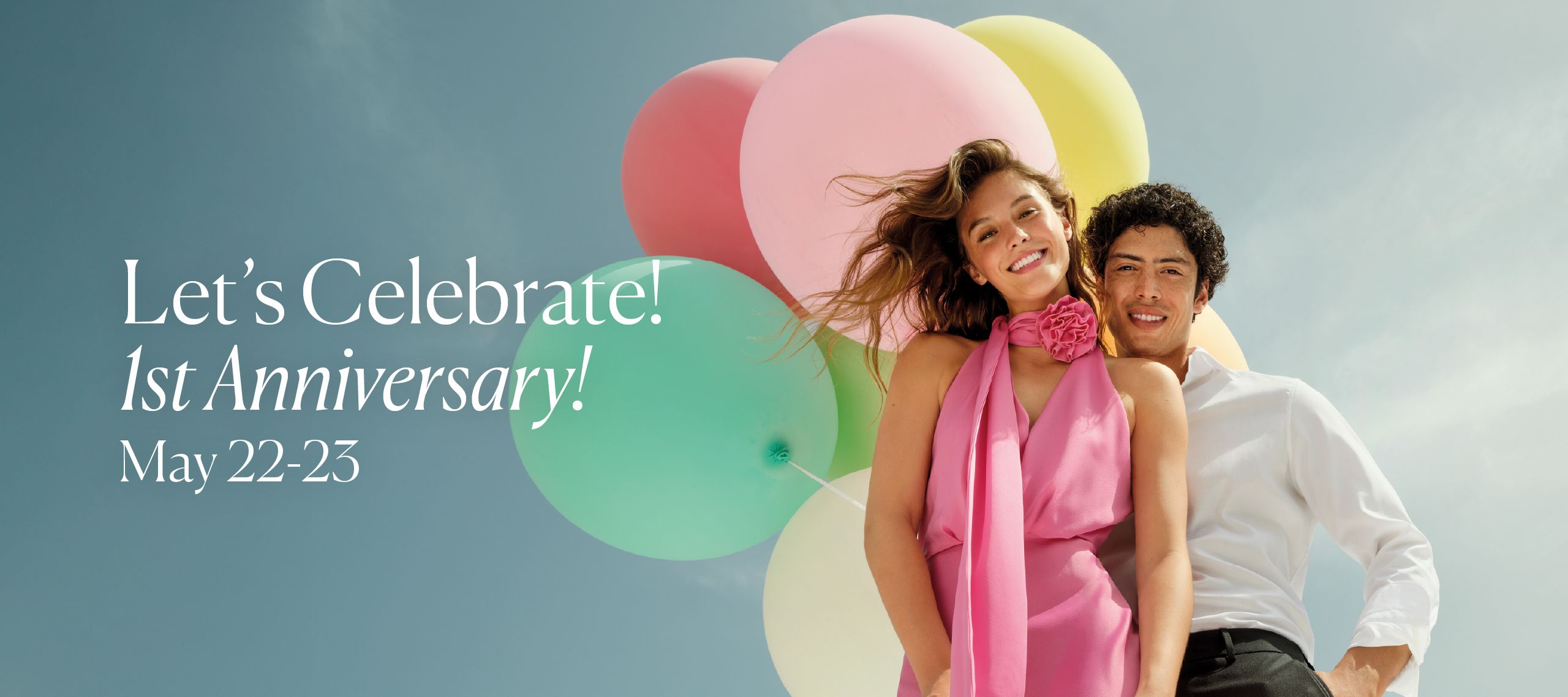 A couple of young people smiling in front of colorful balloons, celebrating the first birthday, with the text 'Let's celebrate together! 1st Birthday starting from May 22nd.