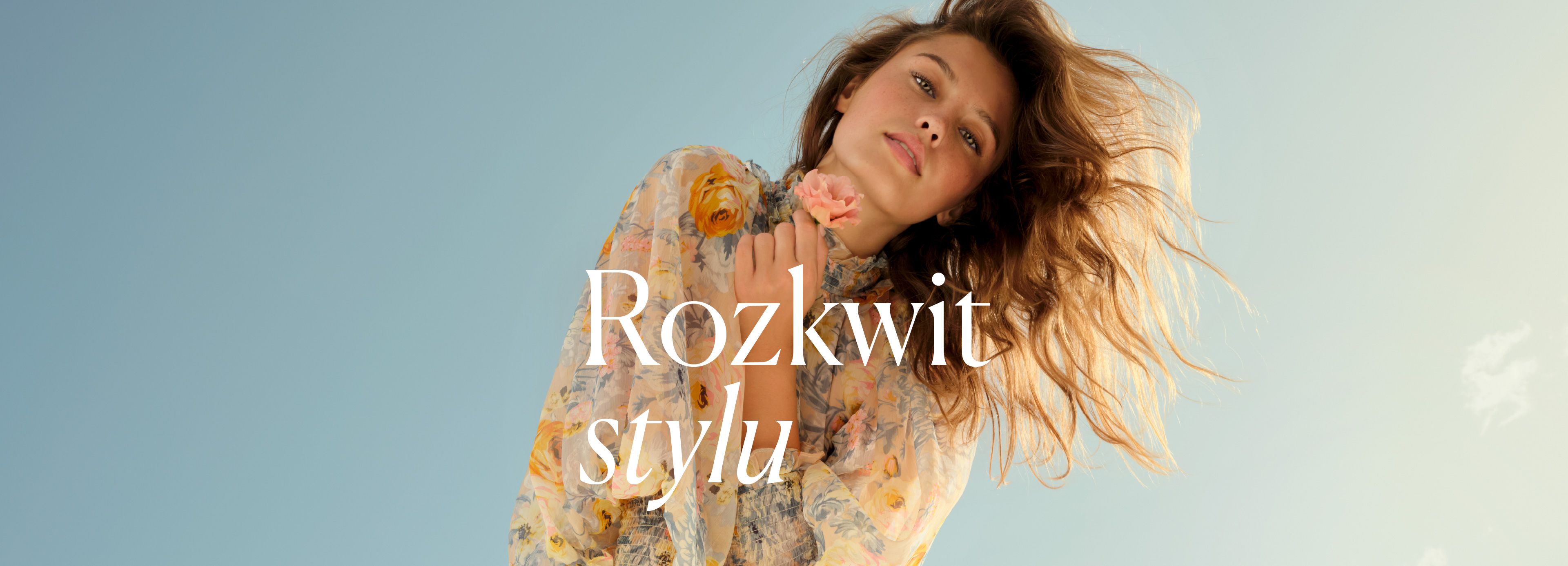 Elegancka kobieta w kwiecistej sukience na tle nieba