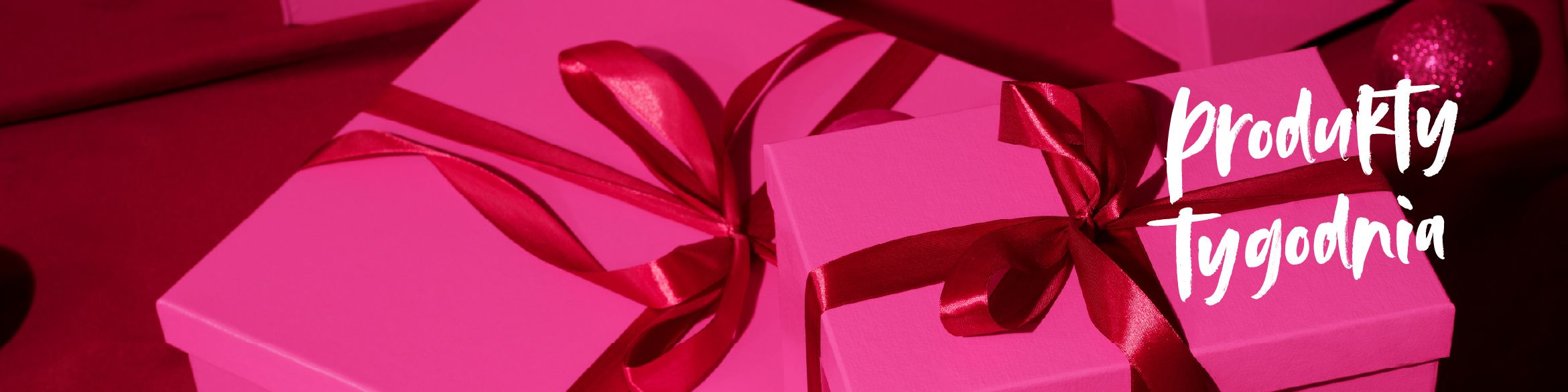 Różowe prezenty ozdobione czerwoną wstążką na tle o tym samym kolorze, z napisem 'PRODUKTY TYGODNIA'.