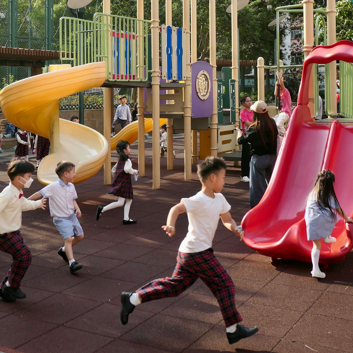 Dzieci bawiące się na placu zabaw ze zjeżdżalniami.