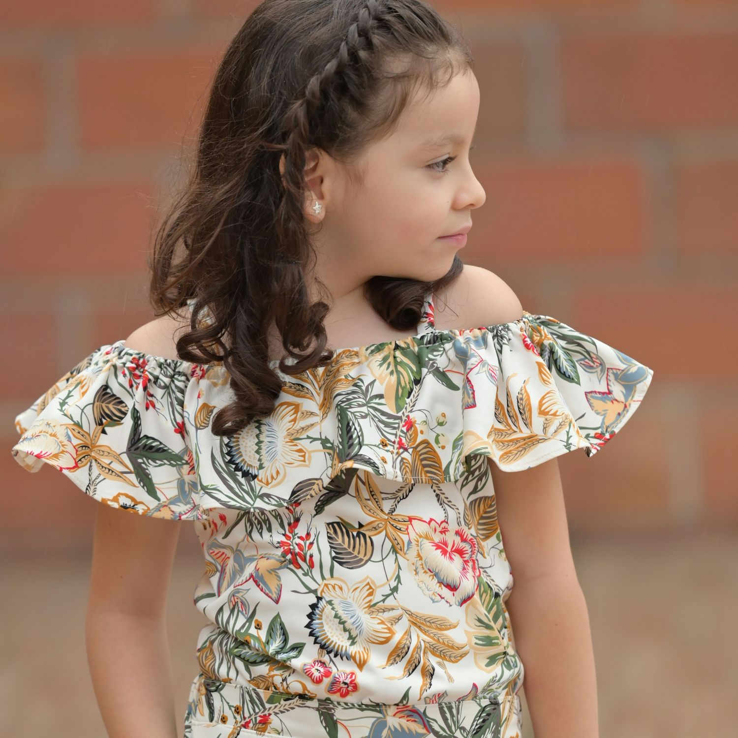 Dziewczynka w sukience w kwiatowy wzór patrząca w bok.