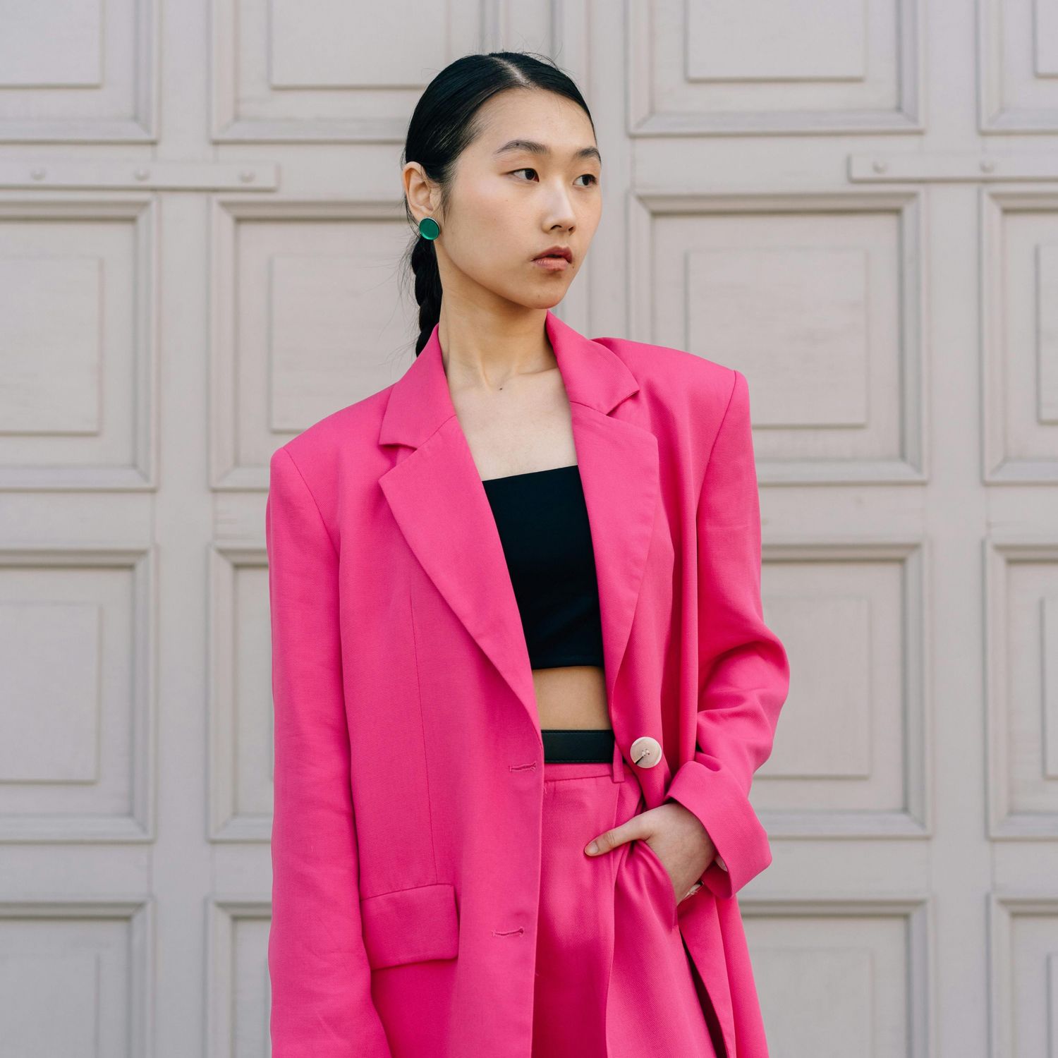 Modelka w różowym garniturze stojąca na tle jasnej ściany