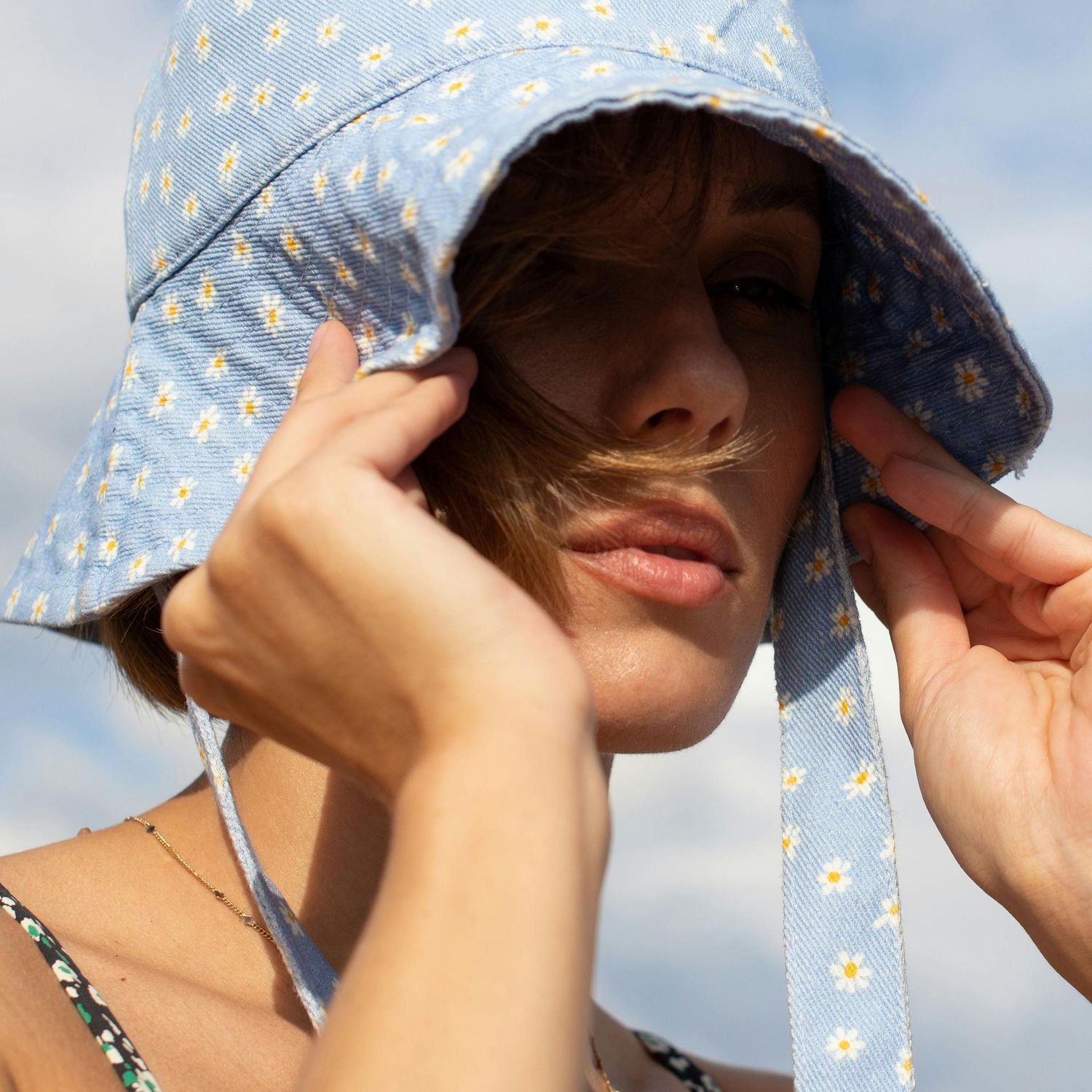 Zbliżenie na kobietę w kapeluszu typu bucket z kwiatowym wzorem.