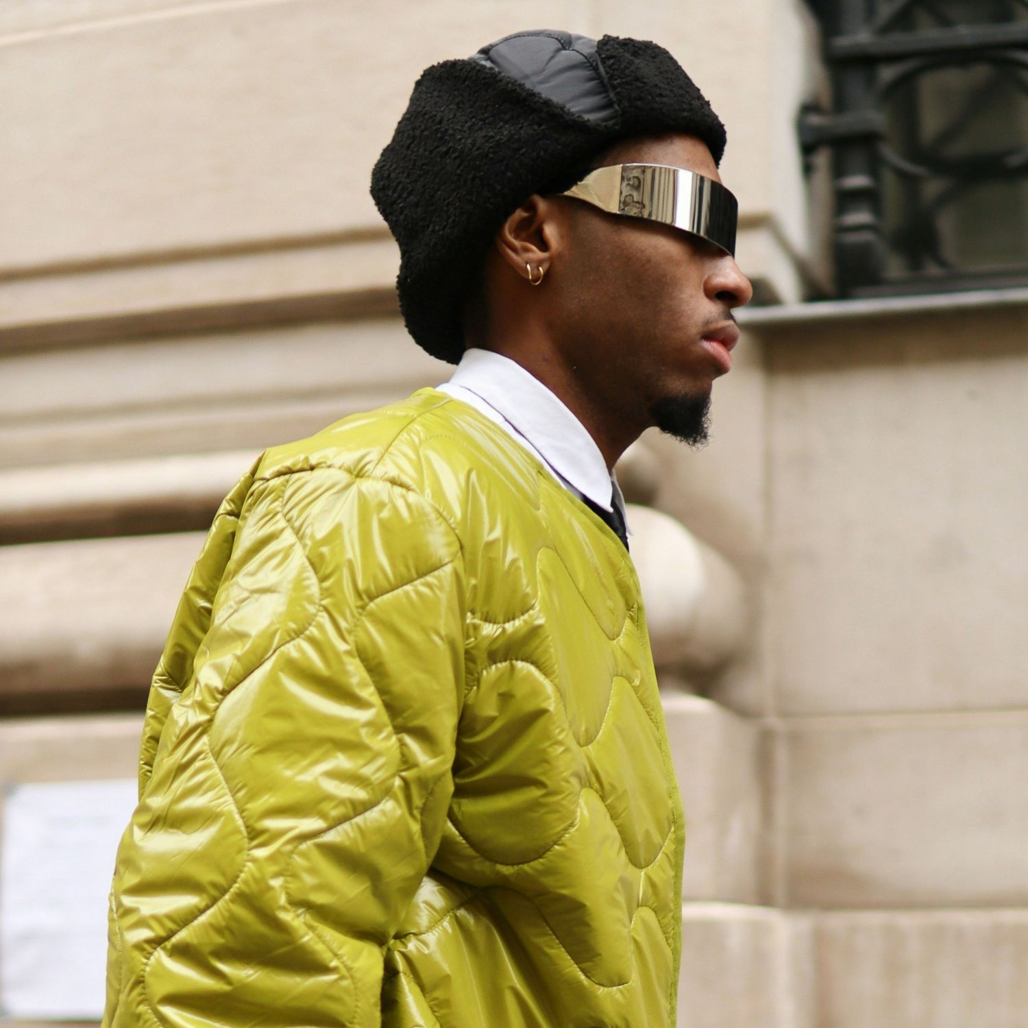 Mężczyzna w zielonej kurtce i futurystycznych okularach na ulicy.