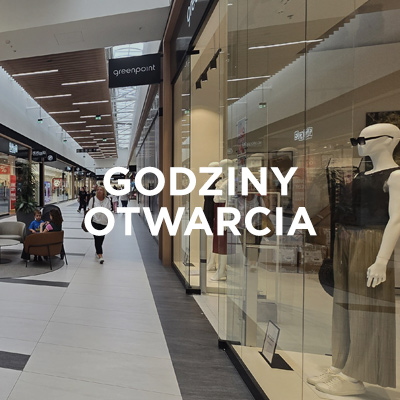 Wnętrze Designer Outlet Kraków z widoczną witryną sklepu Greenpoint i napisem „Godziny otwarcia” na środku obrazu.