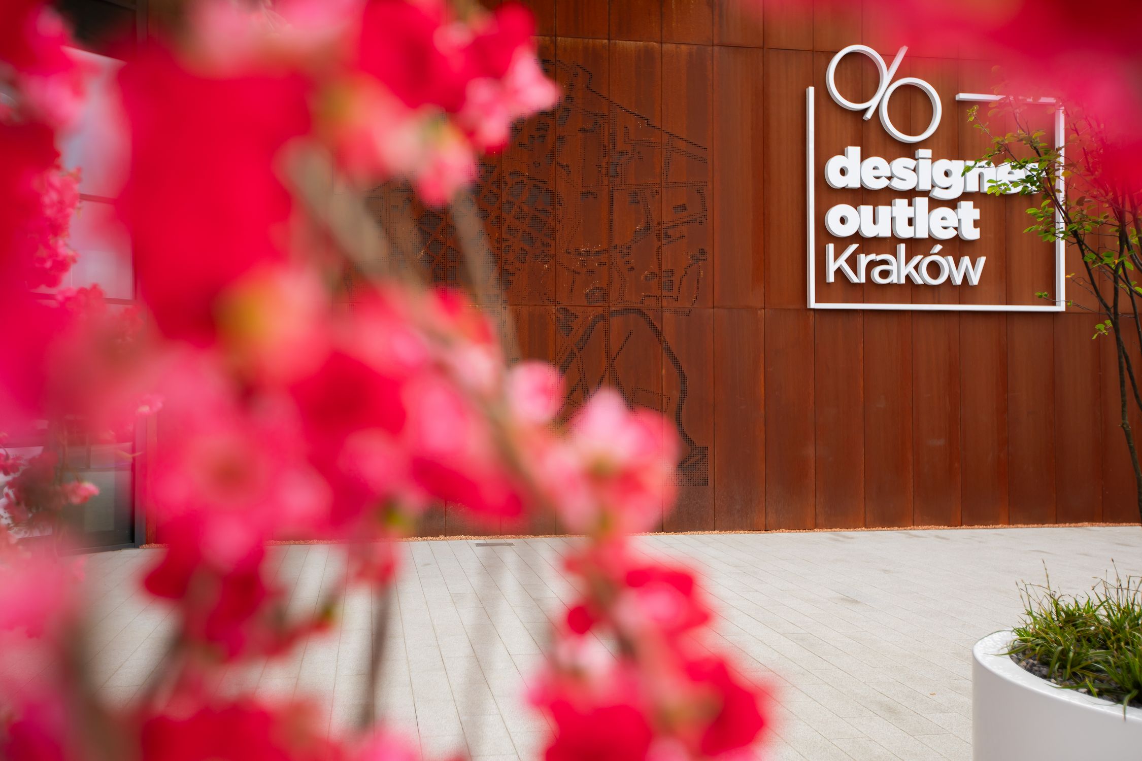 Logo of Designer Outlet Kraków decored with flowers