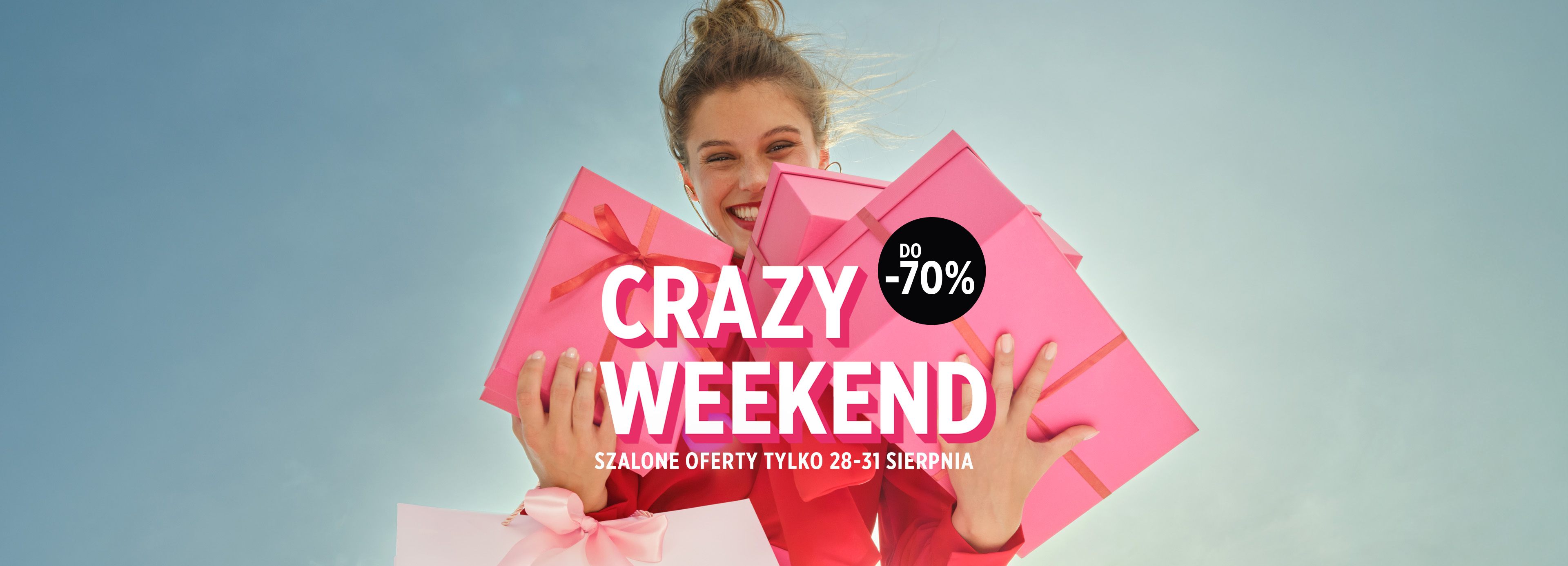 Kobieta uśmiecha się, trzymając różowe prezenty na tle nieba. Po lewej stronie duży napis "CRAZY WEEKEND".