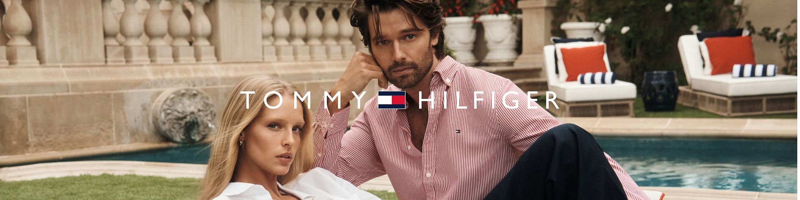Female and male models sitting by a pool in a Tommy Hilfiger advertisement.